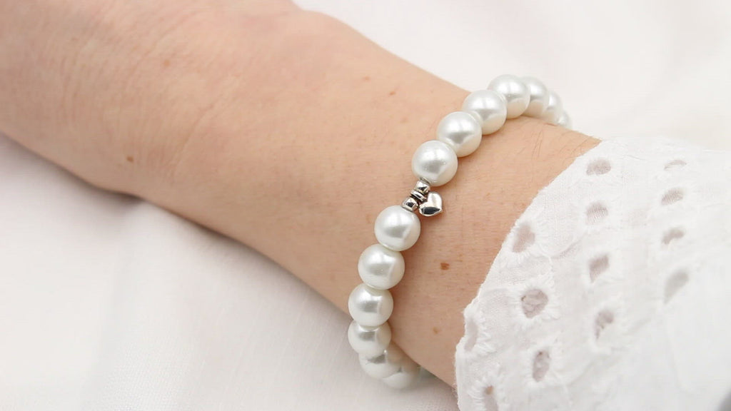Video Perlenarmband mit Herz Anhänger in silber und weiß perlmutt farbenen Perlen am Handgelenk getragen