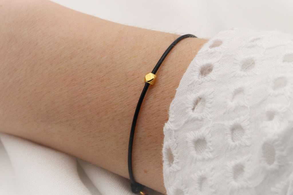 Armband aus Leder mit minimalistischer Perle in Rauten Form am Handgelenk der Frau getragen