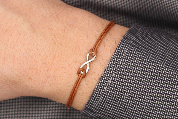 Leder Armband Infinity silber für Herren und Damen als unisex Armband am Handgelenk des Mannes  getragen