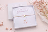 Rosenholz farbenes Makramee Armband mit goldfarbenem Herz in einer weißen Schmuckschachtel mit Karte für das Blumenmädchen zur Hochzeit zu fragen