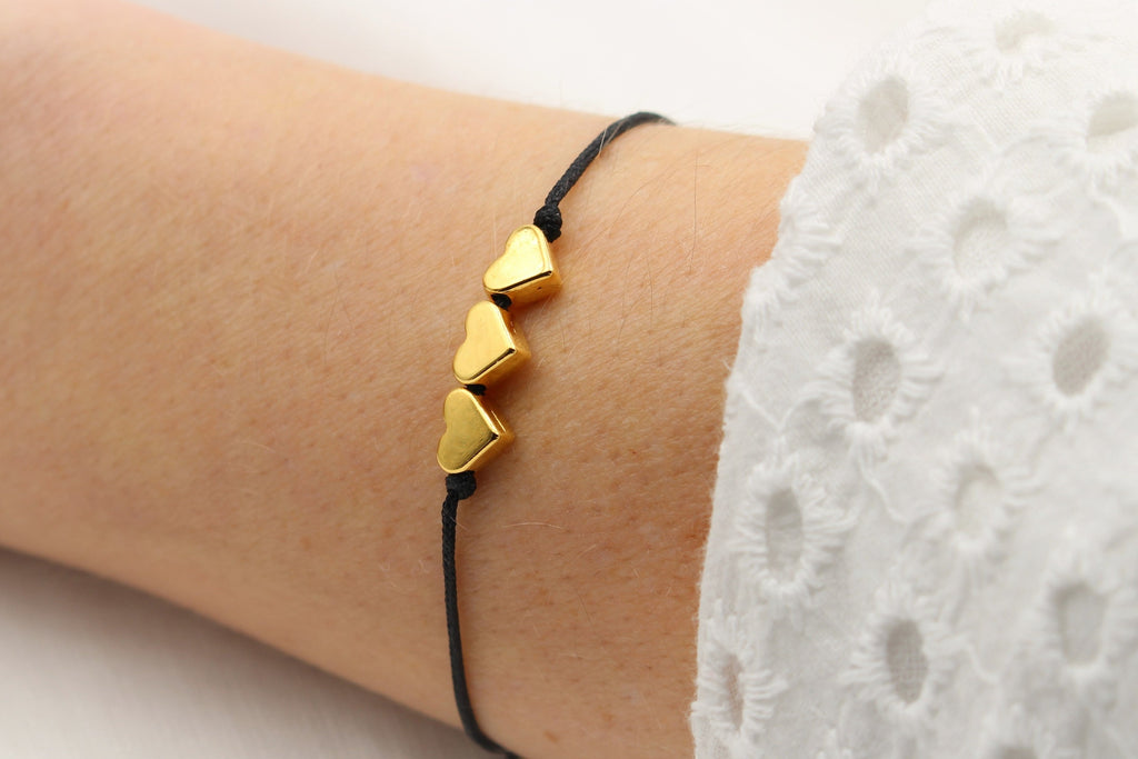 Armband 3 Herzen in goldfarben mit schwarzem Makramee Band am Handgelenk getragen