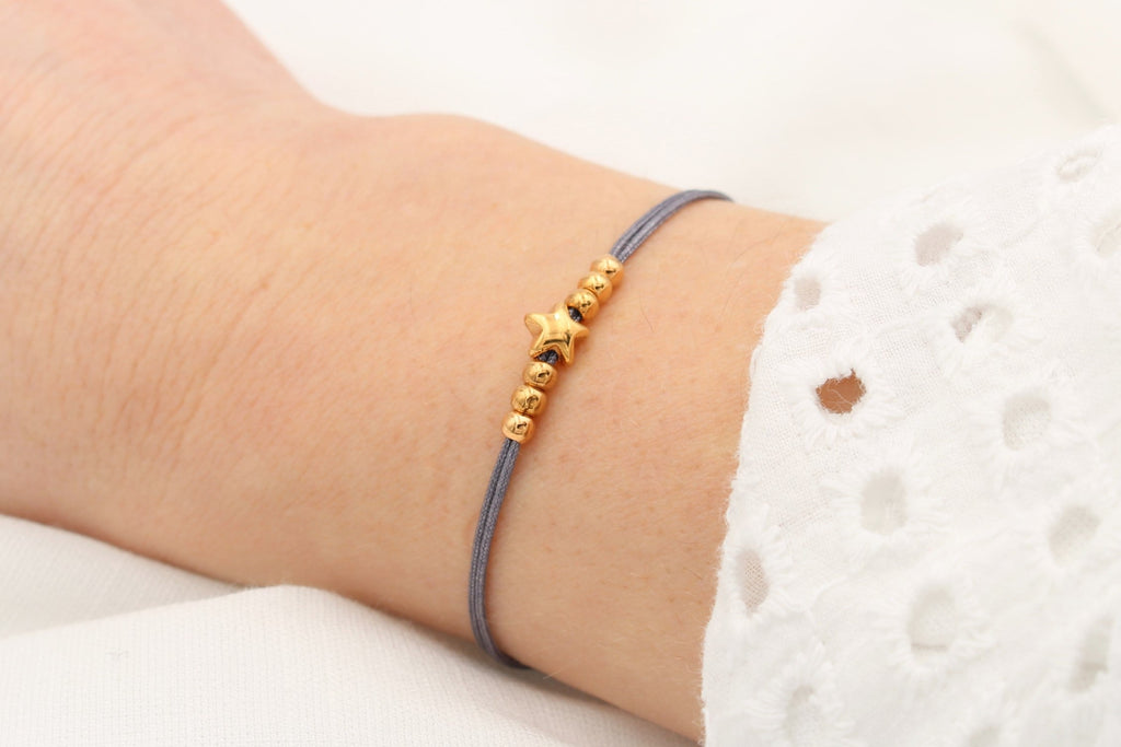 dunkel graues Armband Stern  und Perlen in rosegoldfarben am Handgelenk getragen