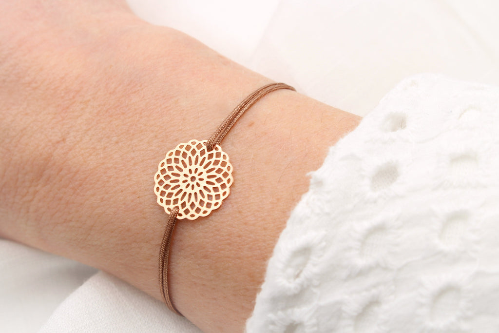 braunes Armband mit Blume des Lebens in rosegold am Handgelenk getragen