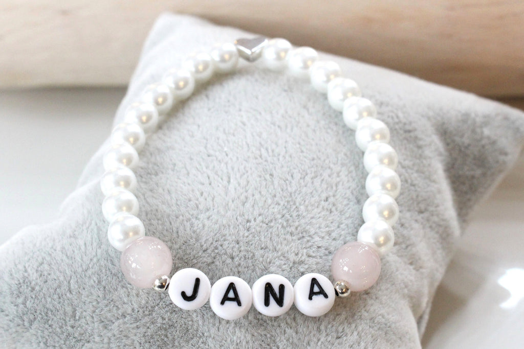 weiß perlmutt farbenes Perlenarmband mit Namen und rosa sowie silberne Details als Geschenk für Mädchen