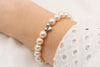 Armband aus rosa perlmutt farbenen Perlen mit silbernem Herz Anhänger am Handgelenk der Frau getragen