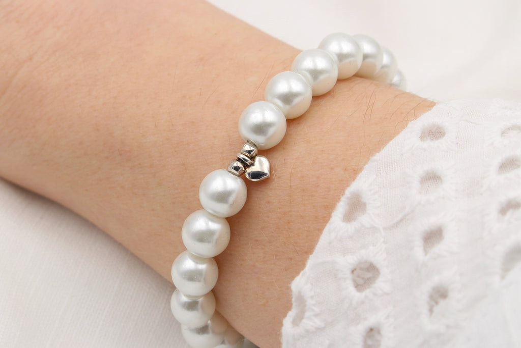 Armband aus Perlen in weiß perlmutt und Herz Anhänger silber am Handgelenk getragen