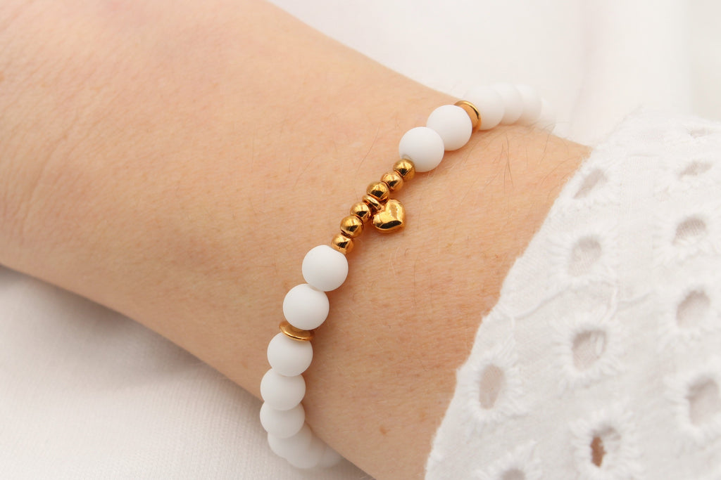 Perlenarmband weiß mit Herz Anhänger rosegold und kleinen Perlen am Handgelenk der Frau getragen