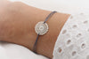 dunkel graues Armband mit silberner Blume im Bohostyle am Handgelenk getragen