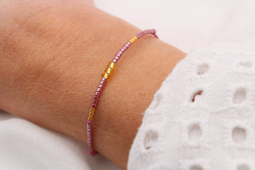 Zartes Makramee Armband mit Miyuki Delica Glasperlen in Burgundy goldfarben am Handgelenk der Dame