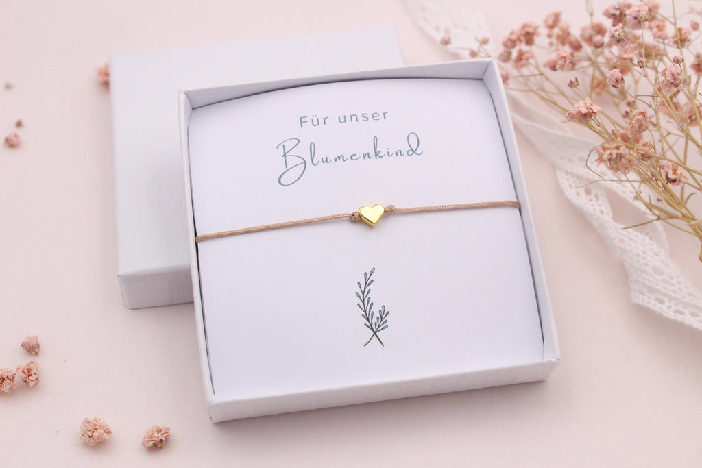 Blumenkind fragen mit einem Makramee Armband mit Herz in goldfarben und einer kleinen weißen Geschenkbox sowie passender Karte "Für unser Blumenkind"