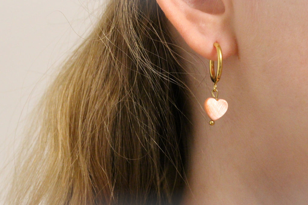 Creolen mit Herz Muschel Anhänger in rose und goldfarben am Ohr getragen