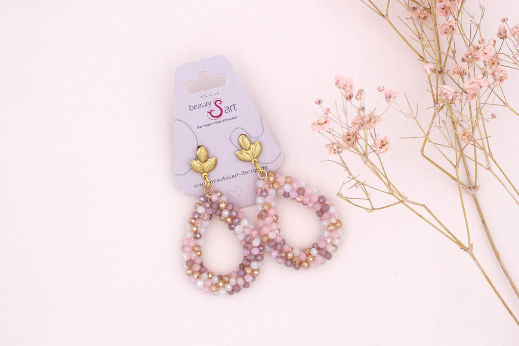 lange, glitzernde Perlen Ohrringe in gold mit rosa schimmernden Tönen.