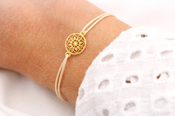 beiges Mandala Armband mit goldener Rosette am Handgelenk der Frau getragen