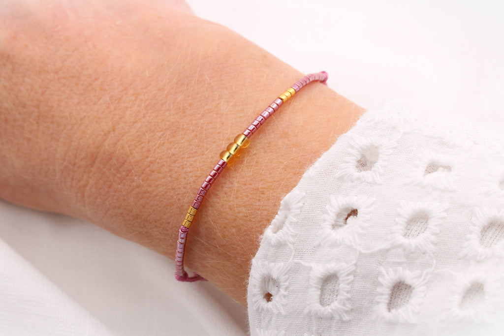 Schiebeknoten Armband mit Perlen in Burgund und gold am Handgelenk der Dame getragen