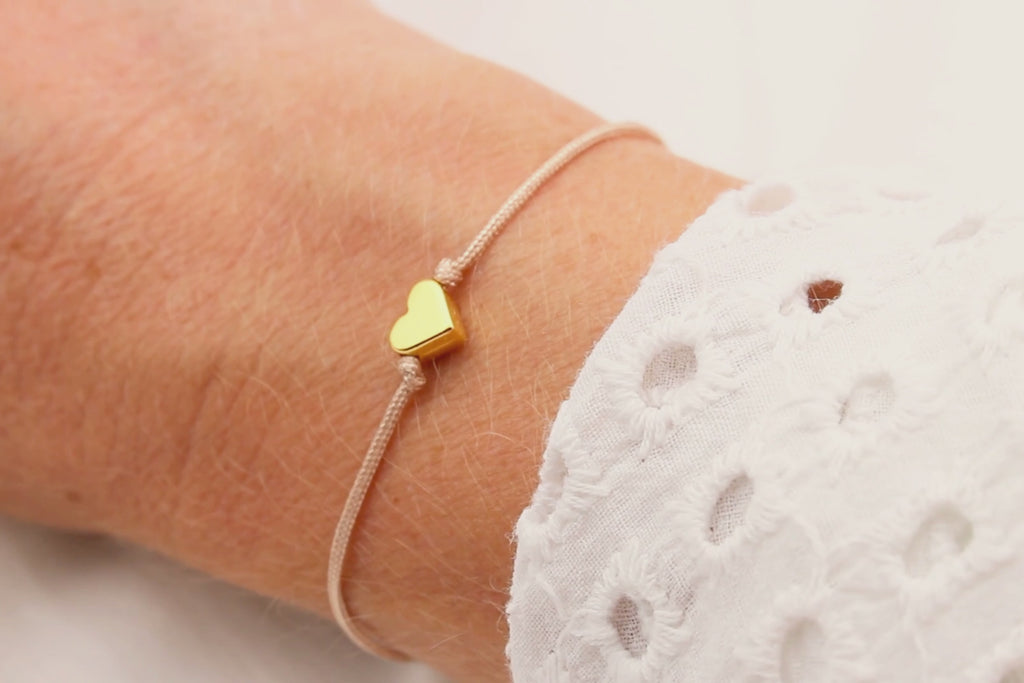 Video des Makramee Armband in rosenholz mit rosegodlfarbenem Herzen am  Handgelenk der Frau getragen