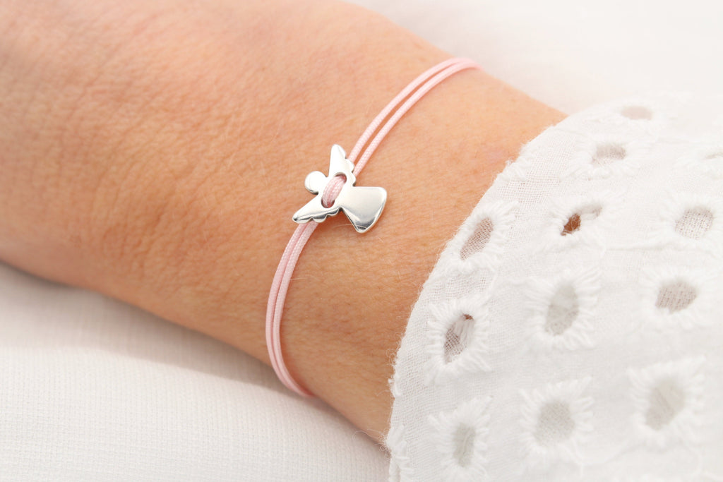 Rosa Schutzengel Armband mit silberfarbenem Schutzengel Anhänger am Handgelenk der Frau getragen
