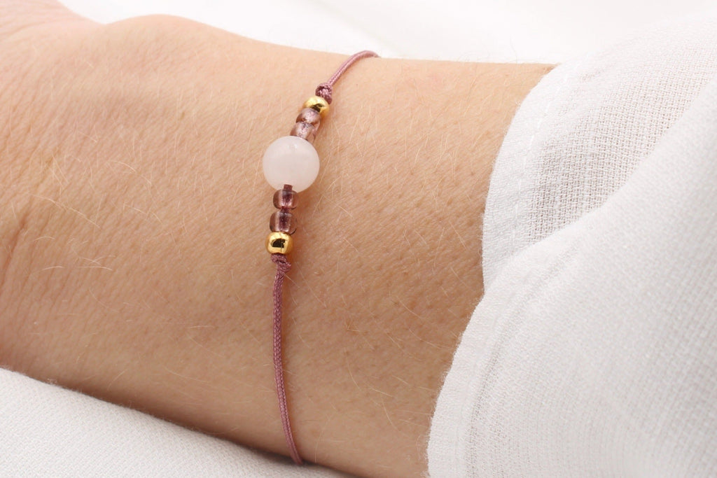 zartes Armband aus Makramee und Halbedelstein Perle Jade in hell rosa am Handgelenk getragen, Bandfarbe in Beerentönen