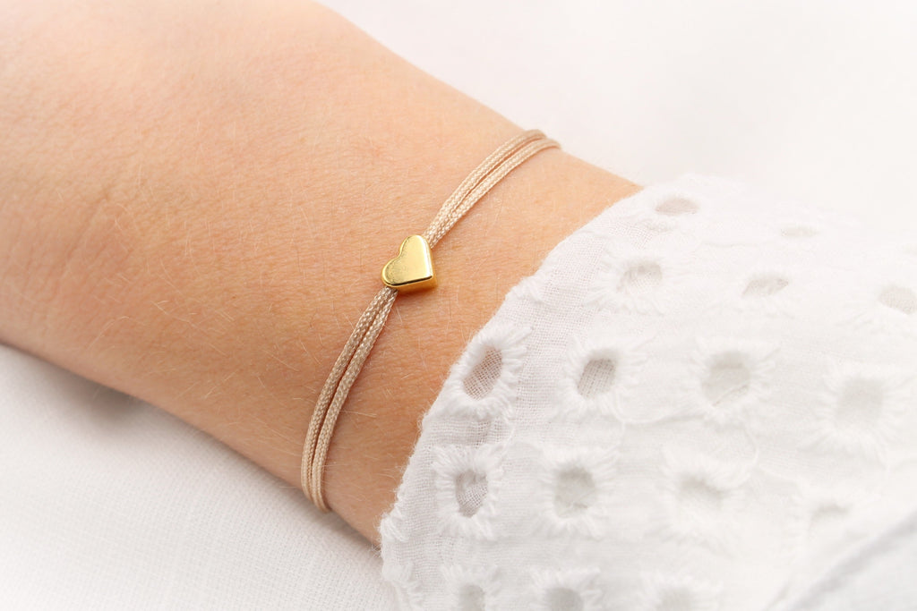 filigranes Makramee Armband Herz gold am Handgelenk der Frau getragen und verstellbarem Verschluss als Freundschaftsarmband für die Freundin