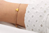 Armband aus Leder für Damen in Rosenholz perlmutt mit goldfarbenem Herz am Handgelenk getragen